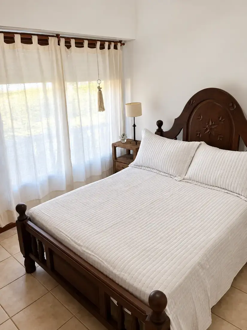 Habitación con cama de madera y cortinas claras