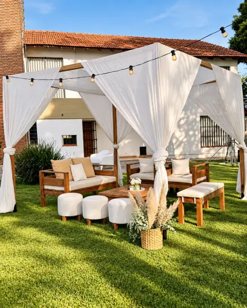 Sillones bajo una pérgola con cortinas blancas en el parque